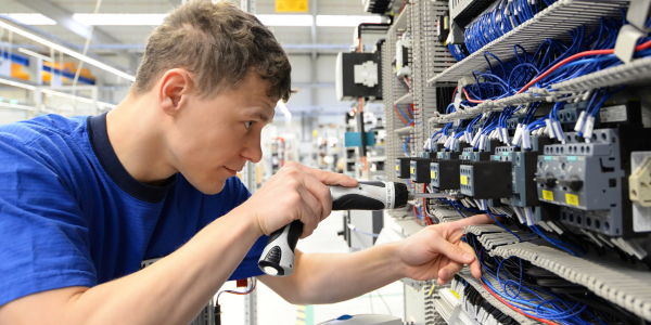 Elektrotechniker bei der Arbeit hält Akkuschrauber in der Hand.